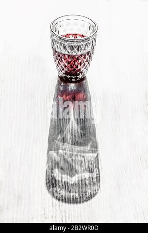 Effetto ottico 3d di un bicchiere di vino rosso con ornamenti romboidi che creano la forma di vaso. Foto Stock