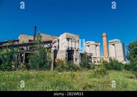 Vecchia fabbrica abbandonata overgrown di cemento armato. Foto Stock