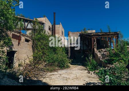 Vecchia fabbrica abbandonata overgrown di cemento armato. Foto Stock