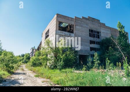 Vecchia fabbrica abbandonata overgrown di cemento armato. Foto Stock