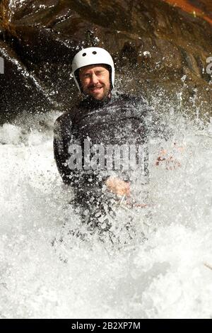 Uomo adulto scendendo in una cascata di sparare dal livello di acqua Foto Stock