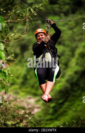 Oversize - Donna Per Adulti Su Zipline Trip Focus Selettivo Contro La Foresta Pluviale Offuscata Foto Stock