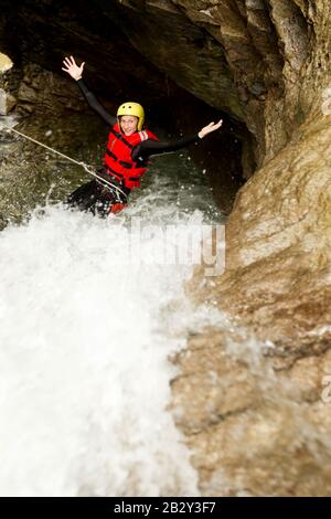 Matura Femmina Indossare Seal Equipment Descending A Waterfall Foto Stock
