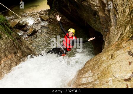 Femminilità Matura Indossando Attrezzature Impermeabili Descendendo Una Cascata Foto Stock
