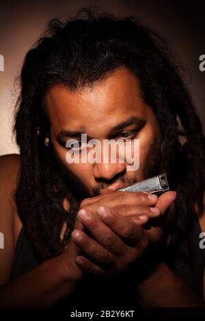 Rastafarian Man Playing Mouth Harmonica Foto Stock