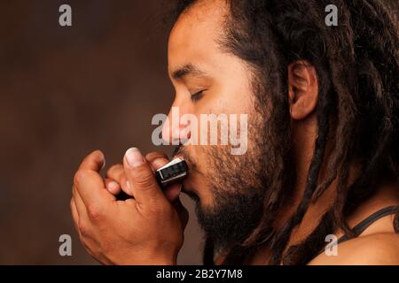 Rastafarian Man Gaming Lip Armonica Foto Stock