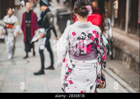 Giovani donne che indossano il tradizionale kimono giapponese con gli alberi di acero colorati in autunno è famoso in foglie di colore autunnale e fiore di ciliegio in primavera, Kyo Foto Stock