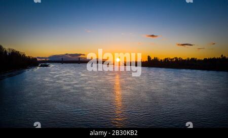Antenna di sole che tramonta sul ponte di fiume sullo sfondo Foto Stock