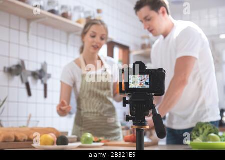Fotocamera professionale digitale mirrorless registrazione video blog di felice coppia caucasica cucina in sala cucina, fotocamera per fotografo o video Foto Stock