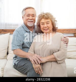 Ritratto di anziani senior asian coppia felice insieme a casa.anziano uomo braccio abbraccio donna anziano spalla guardare la fotocamera. Foto Stock