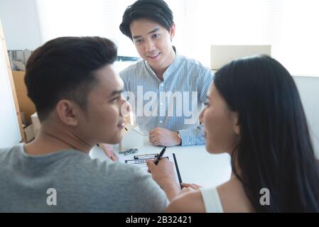 Incontro con agente in ufficio, acquisto affitto appartamento o casa, gli acquirenti di immobili pronti per concludere un affare, famiglia giovane stringono le mani con il real Foto Stock