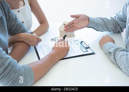 Incontro con l'agente in ufficio, l'acquisto di affitto appartamento o casa, acquirenti di beni immobili pronti a concludere un affare, coppia di famiglia scuotendo le mani Foto Stock