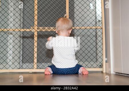 Cute Baby Playing Behind Safety Gate Foto Stock