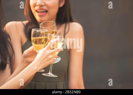 Gruppo di amici asiatici felice giovane donna mano che tiene un bicchiere di vino, cheer e brindisi di vetro in festa cena in pub o ristorante. Foto Stock