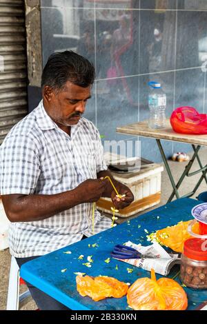 Uomo locale che fa ghirlande di fiori per la preghiera nel vicino Sri Mahamariamman Hindu Temple, Kuala Lumpur, Malesia, Asia Foto Stock