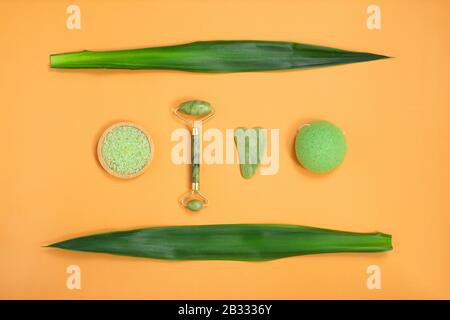 Strumenti per massaggio viso e corpo in pietra di pietre naturali e spugna zero rifiuti per la cura del viso su sfondo giallo Foto Stock