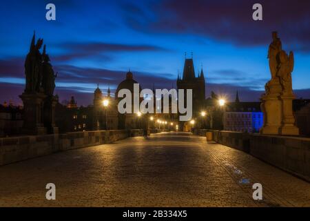 Cielo blu poco prima dell'alba sulla calma, il Ponte Carlo di Poody a Praga. Statue silhouette ed edifici medievali disegnano la famosa linea del paesaggio urbano Foto Stock