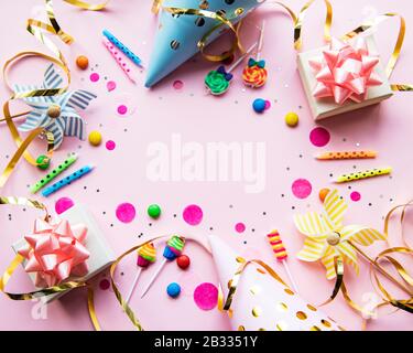 Buon compleanno o party background. Palloncini da compleanno A Posa piatta, confetti e nastri su sfondo rosa. Vista Dall'Alto. Spazio di copia. Foto Stock