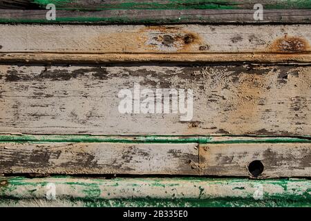 vernice sbucciata su tavole di legno da scafo di una barca, verde e bianco dipinto su tavole di legno, tracce di tempo, vecchie tracce di legno texture di vernice verde Foto Stock