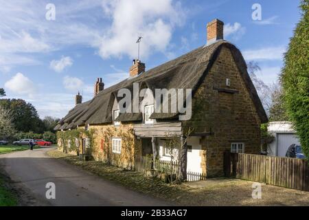 Fila di cottage terrazzati con tetto di paglia nella pittoresca frazione di Brockhall, Northamptonshire, Regno Unito Foto Stock