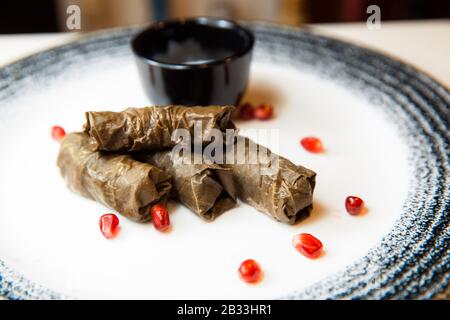 Deliziosa dolma sarma con vitello e bulgur. Carne di vitello con bulgur avvolto in foglie d'uva. Servito con salsa bianca. Cena. Turco greco medio orientale cucina. Foto Stock