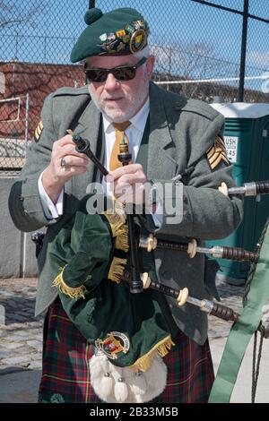 Un membro della contea Cork Pipes & Drums sintonizza il suo strumento prima di marciare nella parata di San Patrizio a Sunnyside, Queens, New York. Foto Stock