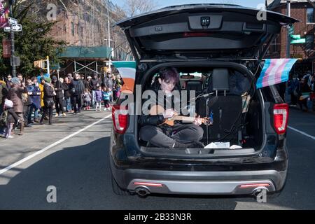 Vicino alla conclusione del giorno di San Patrizio per Tutta la parata, un giovane suona una chitarra nella parte posteriore di un carro della stazione. A Sunnyside, Queens, New York. Foto Stock