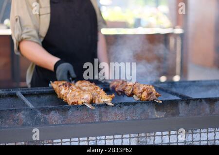 L'uomo arrosti un barbecue su un fuoco aperto.Street food e cucina all'aperto concetto Foto Stock