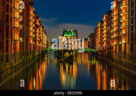 Il quartiere del magazzino Speicherstadt durante il tramonto ad Amburgo, Germania. Magazzini illuminati nel quartiere di Hafencity ad Amburgo. Foto Stock