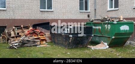 Tappeti ODL, mobili rotti e contenitori per rifiuti nei pressi dell'edificio degli appartamenti Foto Stock