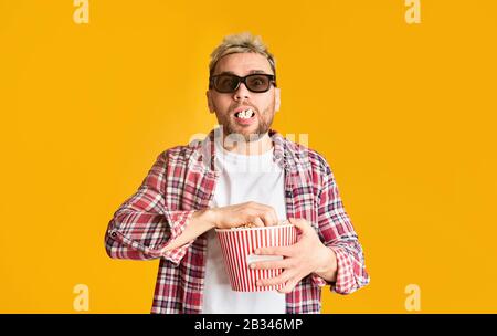L'uomo eccitato in occhiali 3d riempì la sua bocca popcorn Foto Stock