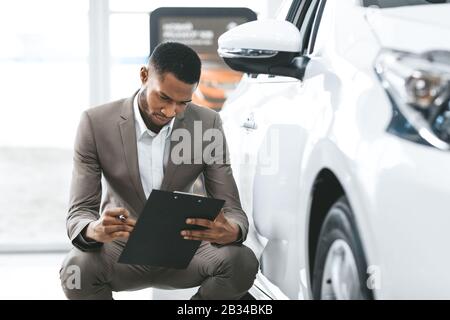 Agente Di Assicurazione Auto Seduto Prendendo Le Note Che Funzionano Nel Centro Di Concessionaria Foto Stock