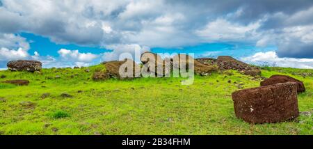 Molte statue moai posate a terra sotto le nuvole Foto Stock