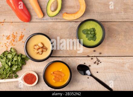 Crema zuppa di zucca e piselli in contenitori di alimenti. Uno sfondo di legno. Concetto di cibo sano e dieta. Foto Stock