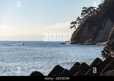 Un surfista guida un'onda verso Capo Imamuragasaki, Sagami Bay, vicino all'Isola di Enoshima, che ospita gli eventi di vela delle Olimpiadi estive di Tokyo 2020 Foto Stock