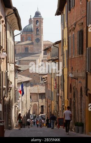 Turisti sulla stretta strada del centro storico di Urbino, Italia. La parte storica della città è dichiarata patrimonio dell'umanità dall'UNESCO Foto Stock