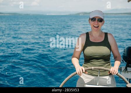 Skipper femmina sul volante di uno yacht. Concetto di vela e nautica da diporto. Foto Stock