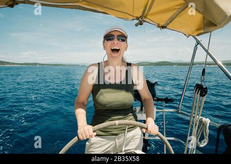 Skipper femmina sul volante di uno yacht. Concetto di vela e nautica da diporto. Foto Stock