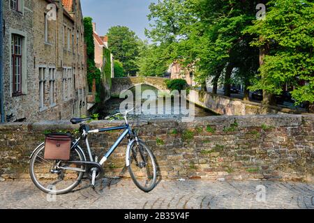 Bicyccle su un ponte vicino al canale e vecchie case. Bruges Brugge , Belgio Foto Stock
