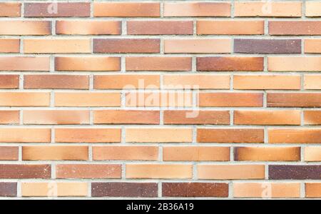 Una parete in mattoni di ceramica con diverse sfumature di marrone e ocra, per fondo o risorsa di materiali da costruzione Foto Stock