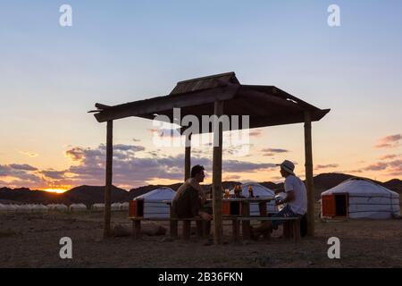 Mongolia, provincia di Dundgovi, distretto di Saikhan Ovoo, due turisti che hanno una birra serale in un campo di yurt vicino alle rovine del monastero Di Ongi Foto Stock