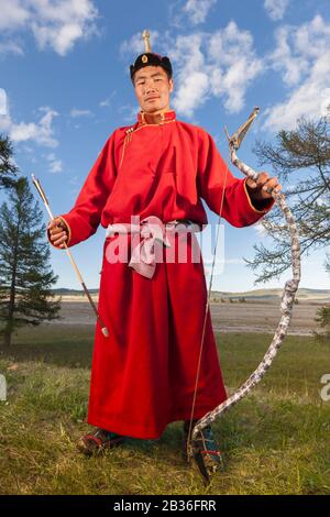 Mongolia, provincia di Khovsgol, Khatgal, festival Naadam, ritratto a tutta lunghezza di un uomo che pratica tiro con l'arco in abiti tradizionali Foto Stock