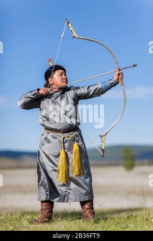 Mongolia, provincia di Khovsgol, Khatgal, festival Naadam, donna che pratica tiro con l'arco in abiti tradizionali Foto Stock