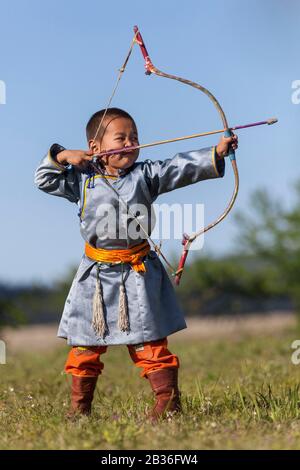 Mongolia, provincia di Khovsgol, Khatgal, festival Naadam, ragazzo in abiti tradizionali che pratica tiro con l'arco Foto Stock