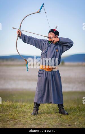Mongolia, provincia di Khovsgol, Khatgal, festival Naadam, uomo che pratica tiro con l'arco in abiti tradizionali Foto Stock