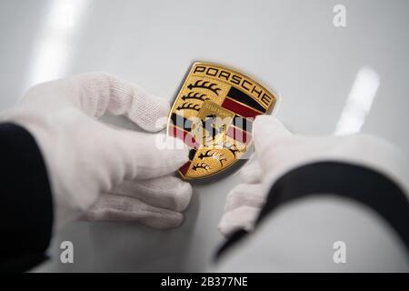 Stoccarda, Germania. 04th Mar, 2020. Un dipendente di Porsche AG detiene un emblema Porsche sul cofano di una Porsche Taycan in produzione. Credito: Marijan Murat/Dpa/Alamy Live News Foto Stock