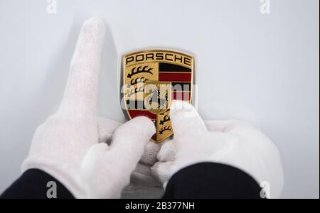 Stoccarda, Germania. 04th Mar, 2020. Un dipendente di Porsche AG detiene un emblema Porsche sul cofano di una Porsche Taycan in produzione. Credito: Marijan Murat/Dpa/Alamy Live News Foto Stock