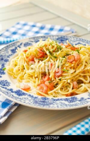 Un piatto di deliziosi spaghetti di pasta con gamberi ed erbe. Immagine verticale Foto Stock