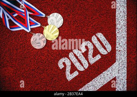Medaglia fissata sulla pista di atletica rossa, sfondo sportivo per l'anno 2020. Evento Multi-Sport Foto Stock