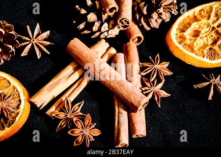 Fondo di fette secche di arancia, cannella e anice stellato, ingredienti per la preparazione di VIN brulé su fondo nero Foto Stock